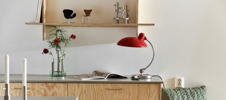 Kaiser Idell-lampa i rött, Ikaru-vas och design från Fritz Hansen i ett stilrent, modernt kök med plywood. 