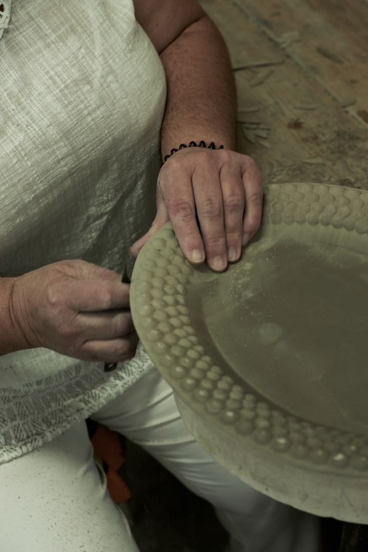 Överflödig lera tas bort från Mateus keramik som är steg 3 i tillverkningsprocessen.