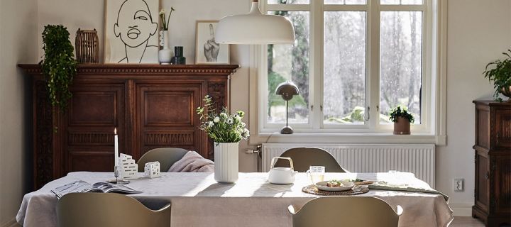 En matplats i klassisk skandinavisk stil med vit taklampa från Northern och olivgröna Harbour stolar från Muuto.