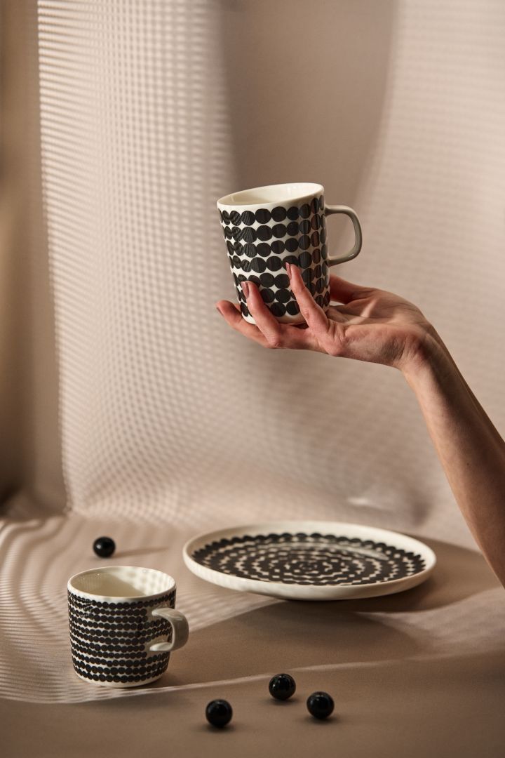 Räsymatto mugg från Marimekko har ett distinkt svart-vitt grafiskt mönster som kommit att bli en modern klassiker bland kaffekoppar för kaffeälskare. Här hand som håller muggen.