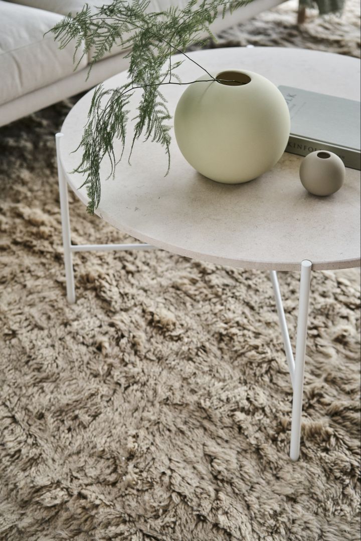 Den ikoniska Ball vasen i färgerna shell och sand står på ett runt soffbord.